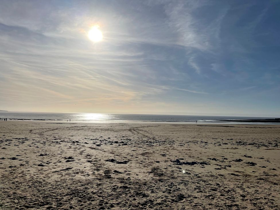A beach with sand and ocean under a sunny sky at 7 Adrian Close in Porthcawl