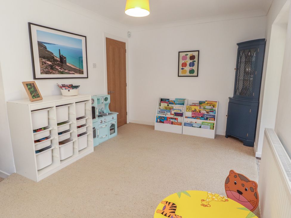 A playroom with a book shelf and toy kitchen at Ty Traeth in Porthcawl