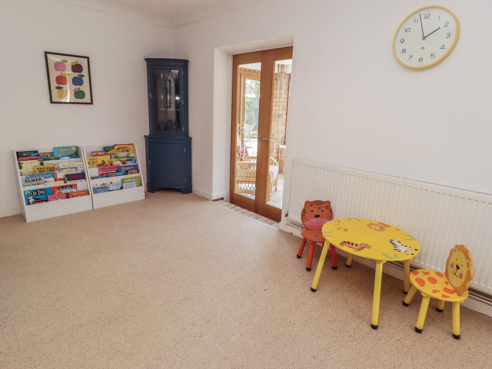 A playroom with a bookshelf and a table with colorful chairs at Ty Traeth in Porthcawl