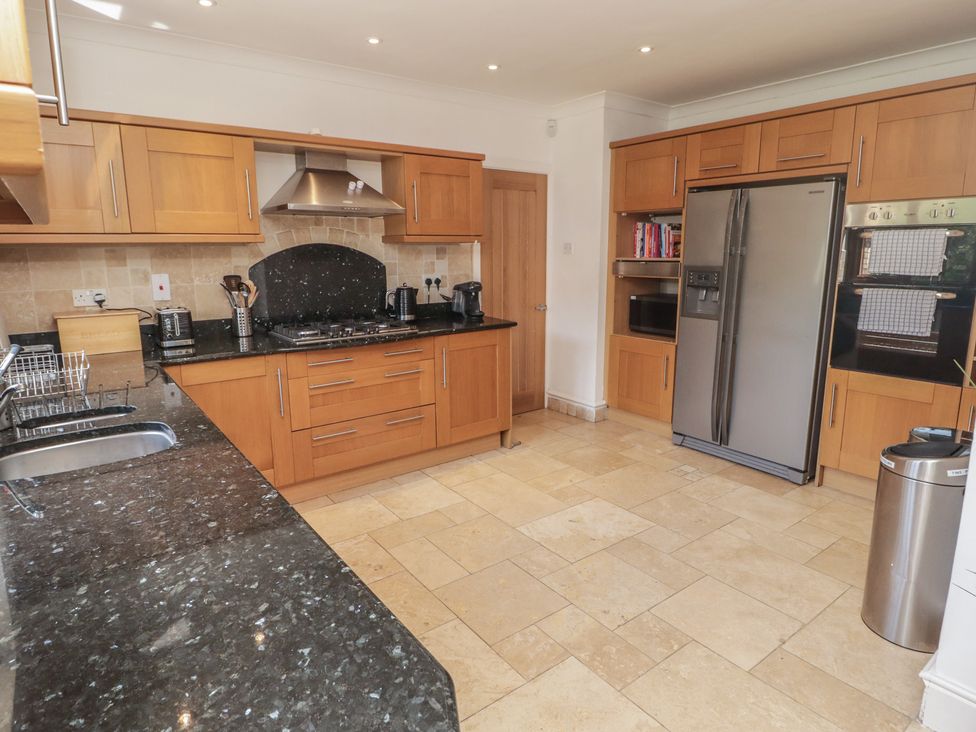A kitchen with wooden cabinetry and appliances at Ty Traeth in Porthcawl