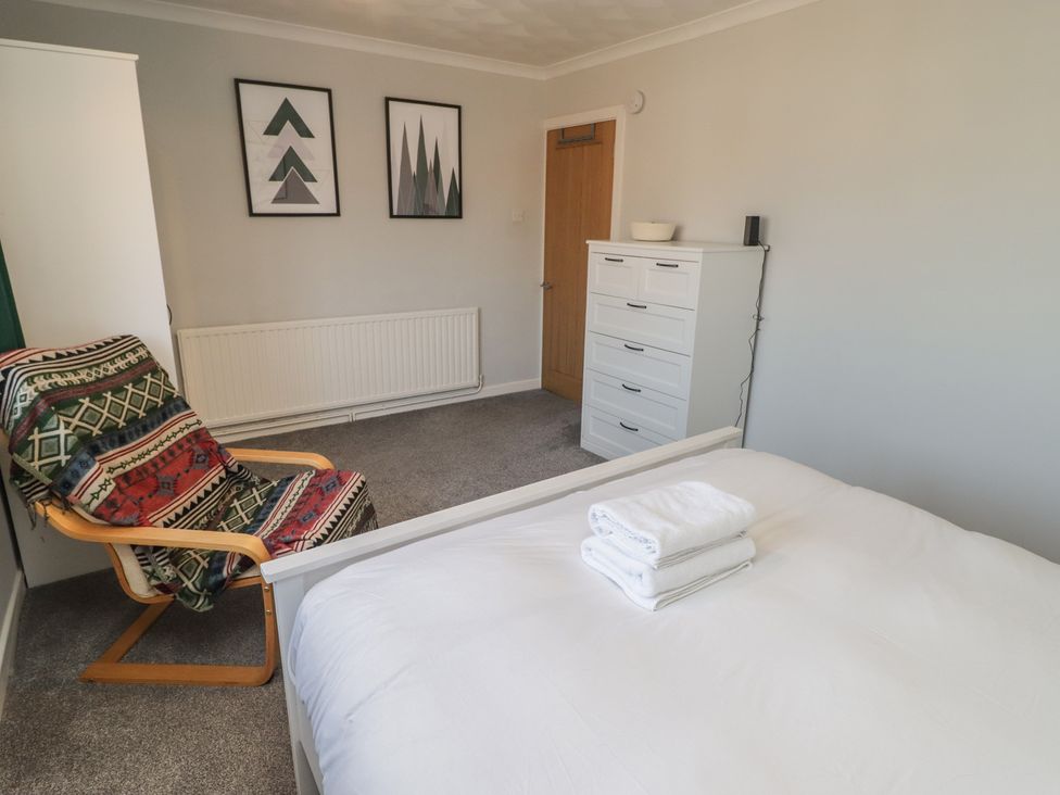 A bedroom with a bed and a chair at Ty Traeth in Porthcawl