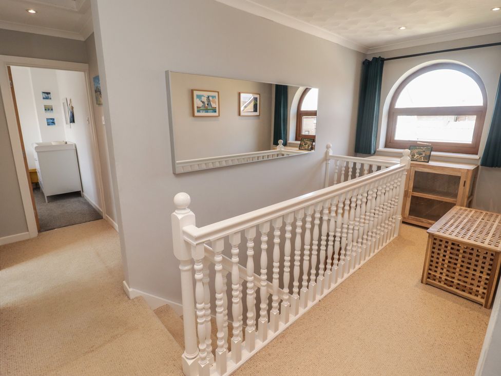 A hallway with a staircase and mirror at Ty Traeth in Porthcawl