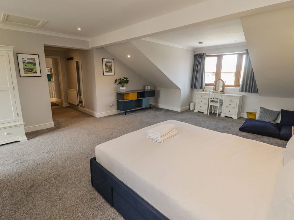 A bedroom with a bed, dresser, chair, and window at Ty Traeth in Porthcawl