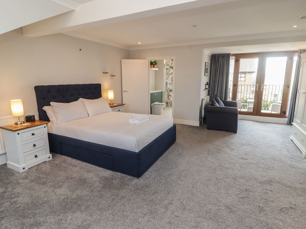 A bedroom with a bed and armchair at Ty Traeth in Porthcawl