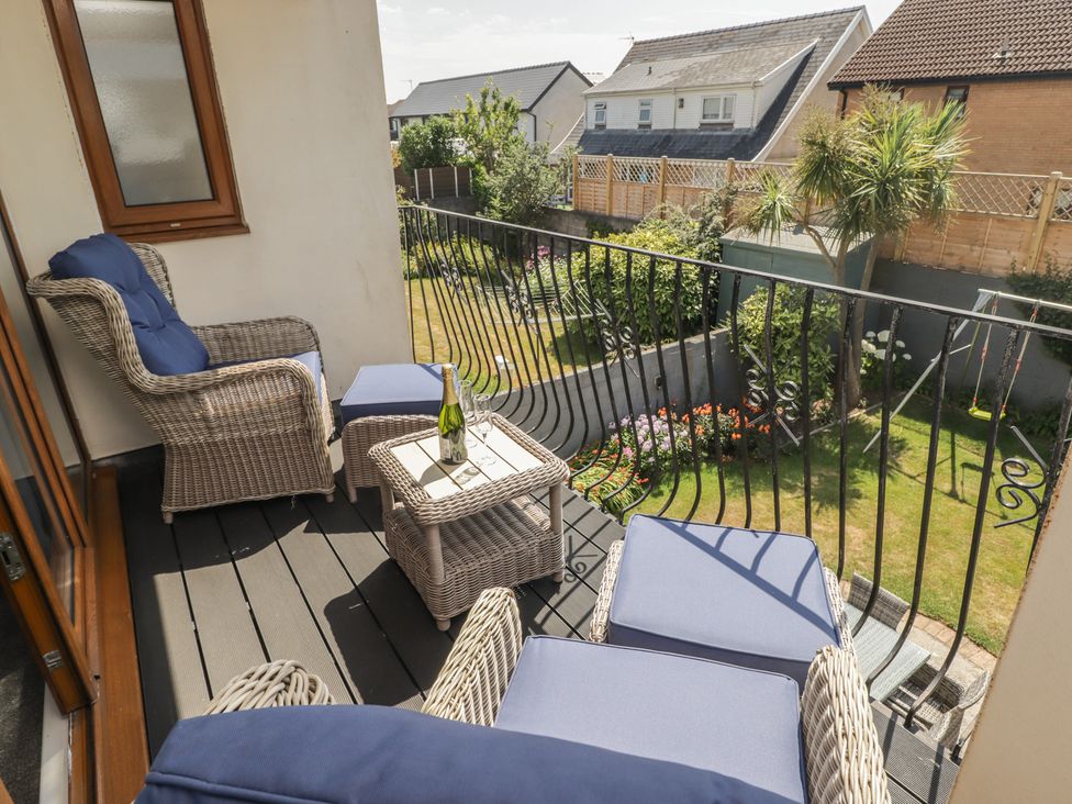 A balcony with wicker furniture and a garden view at Ty Traeth in Porthcawl