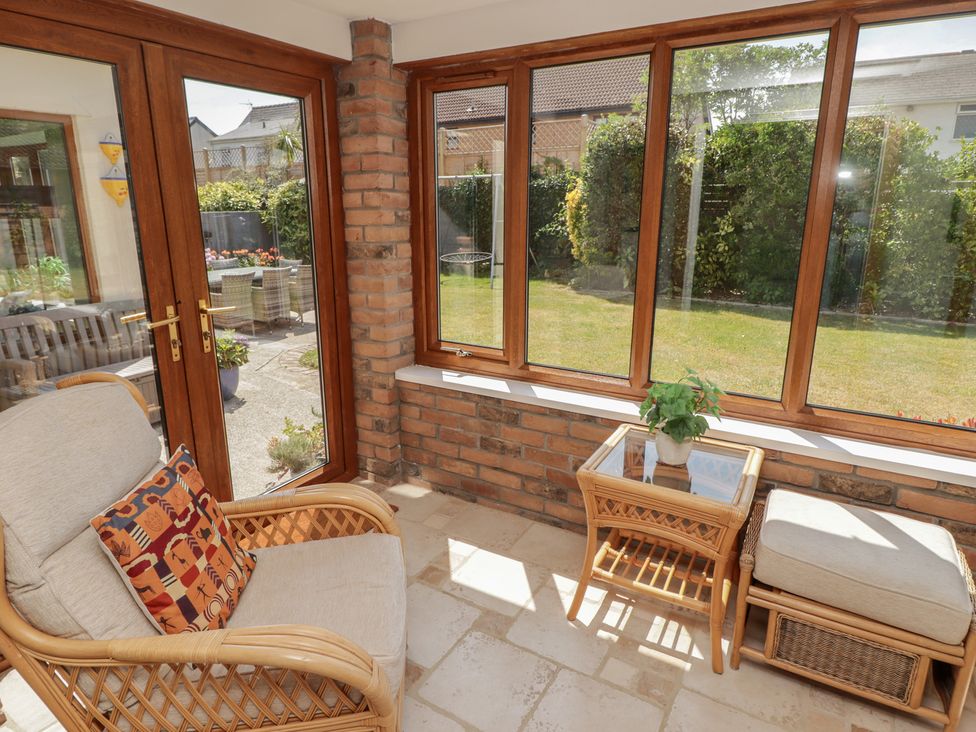 A conservatory with an armchair and a table at Ty Traeth in Porthcawl