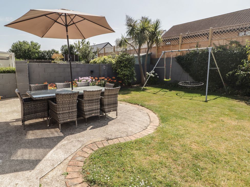 A garden with a dining set and swing set at Ty Traeth in Porthcawl