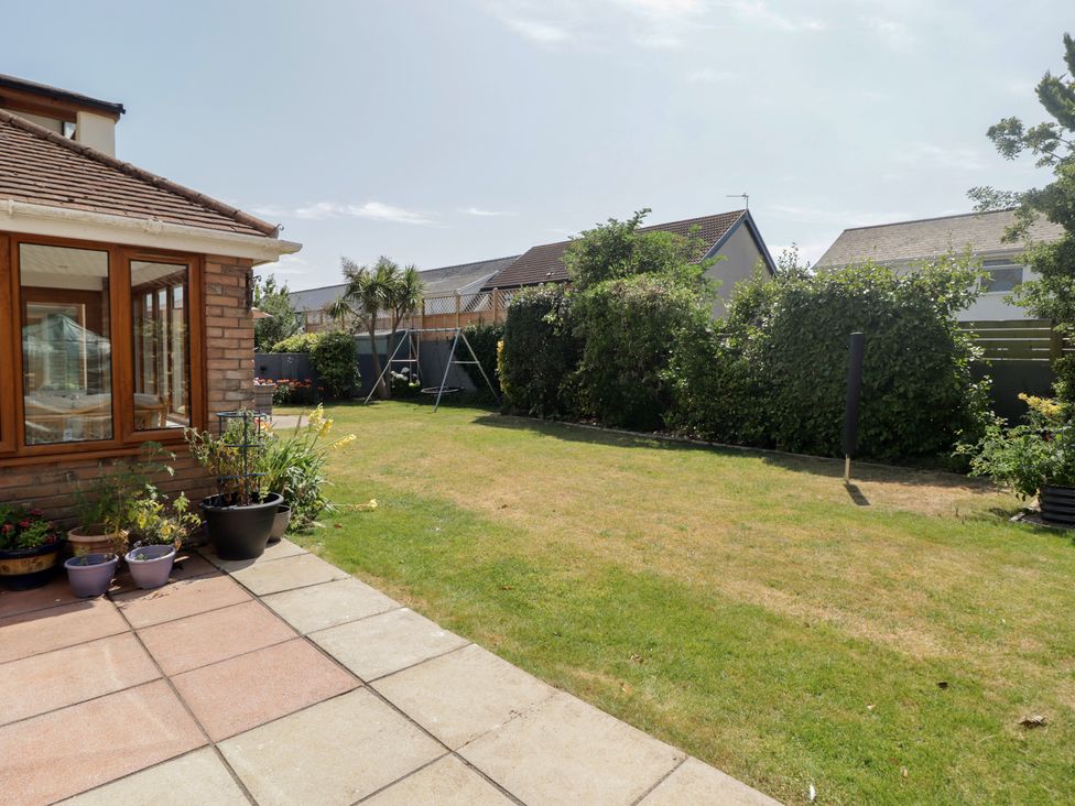 A garden with a swing and house at Ty Traeth in Porthcawl
