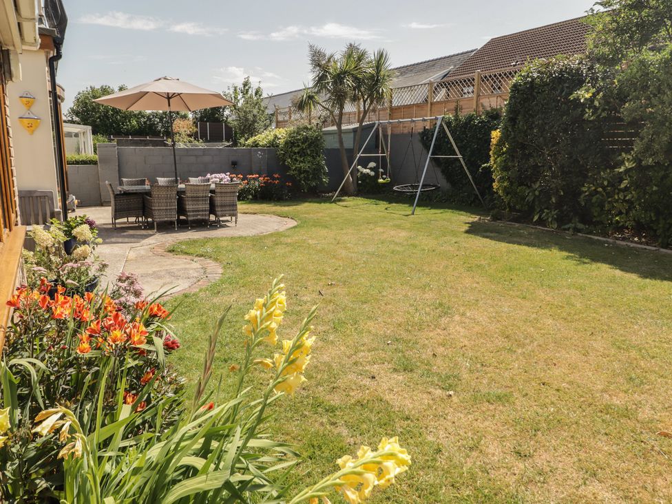 A garden with a table and chairs under an umbrella at Ty Traeth in Porthcawl