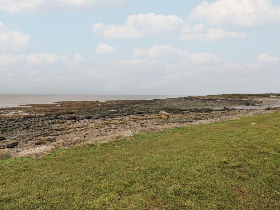 A coastal area with grass and rocks near the sea at Ty Traeth in Porthcawl