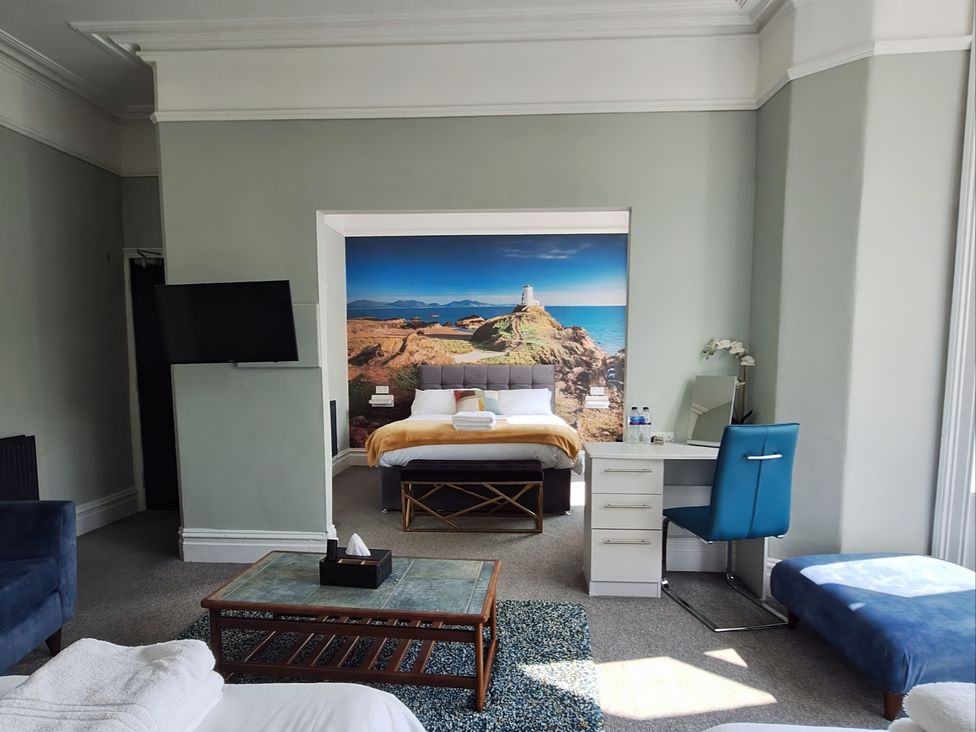A bedroom with a bed, desk, and television at Holiday home guest house, Llandudno