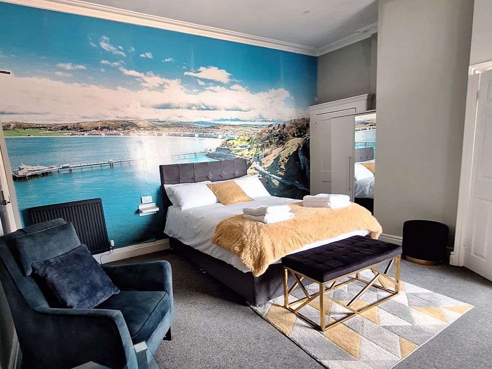 A bedroom with a bed and an armchair at Holiday home guest house in Llandudno