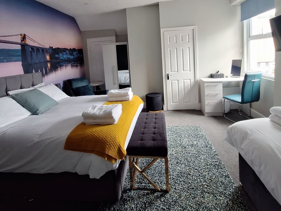 A bedroom with two beds and a desk at Holiday home guest house in Llandudno