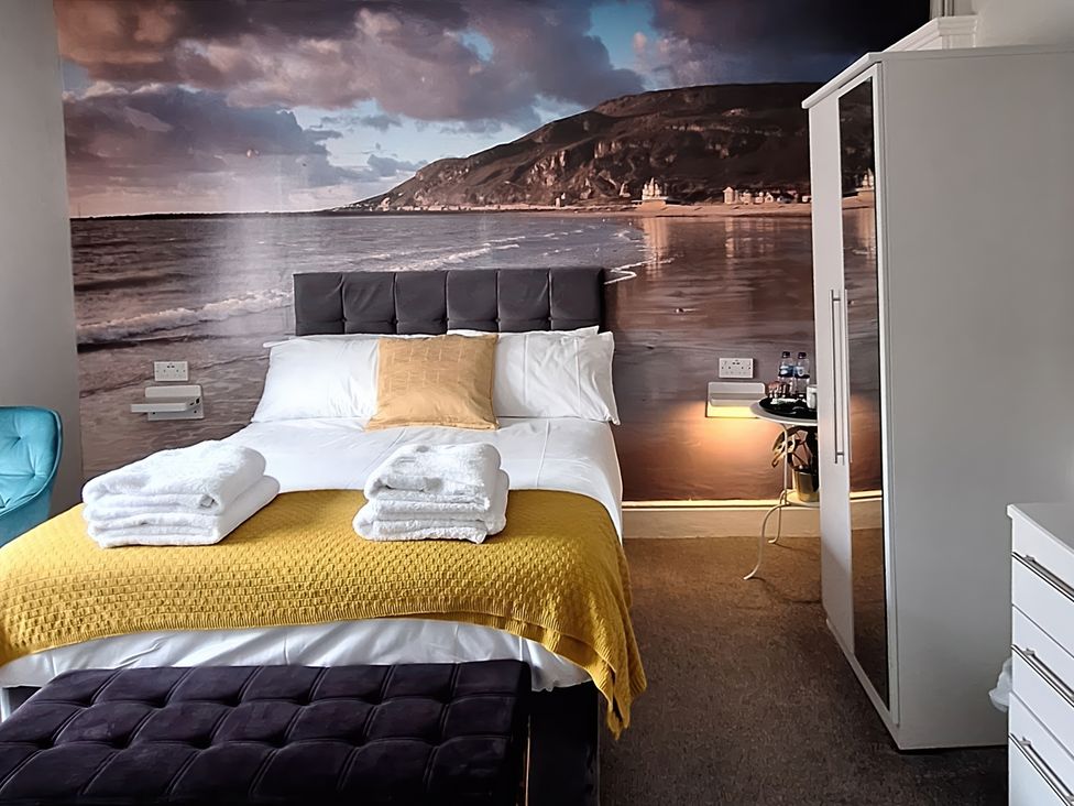 A bedroom with a bed and a wardrobe at Holiday home guest house in Llandudno