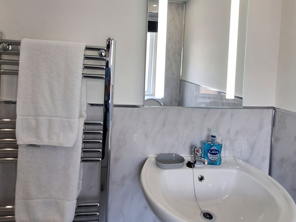 A bathroom with a sink, mirror, and towel rail at Holiday home guest house in Llandudno