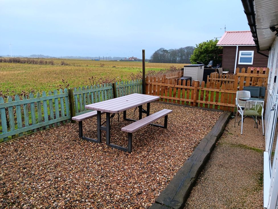 An outdoor seating area with a table and benches at Bay View Chalet 2 Bed Sleeps 4 Pets Garden Beach Wilsthorpe near Bridlington