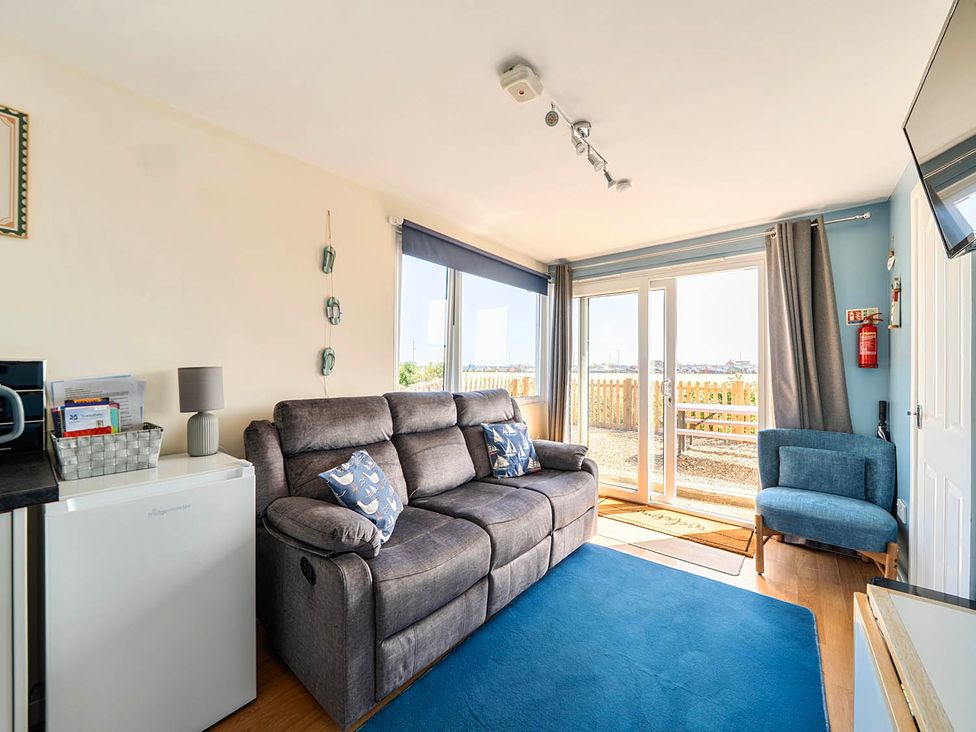 A living room with a sofa, armchair, and kitchenette at Bay View Chalet 2 Bed Sleeps 4 Pets Garden Beach Wilsthorpe near Bridlington