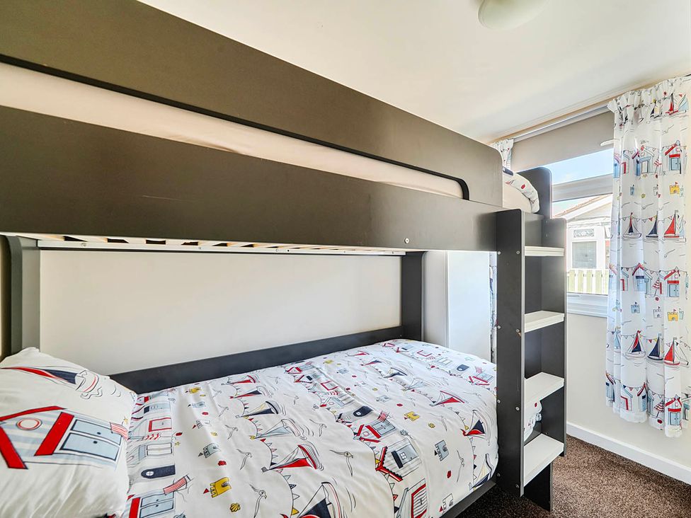 A bedroom with a bunk bed and patterned sheets at Bay View Chalet 2 Bed Sleeps 4 Pets Garden Beach in Wilsthorpe near Bridlington