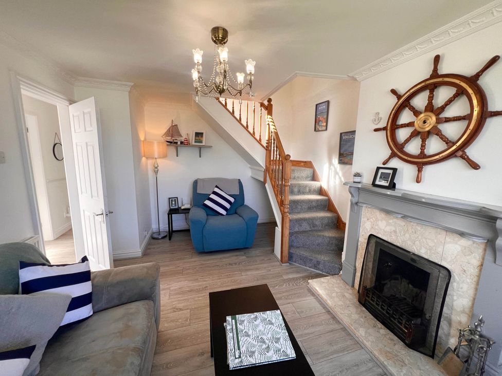 A living room with an armchair and staircase at 2 Bed Family Bungalow, WiFi, Parking, Garden, Dogs, Pentraeth