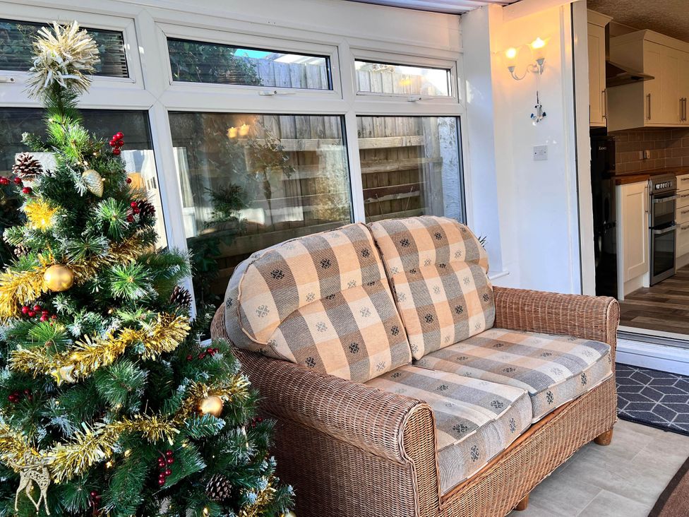 A conservatory with a sofa and Christmas tree at 2 Bed Family Bungalow, WiFi, Parking, Garden, Dogs Pentraeth