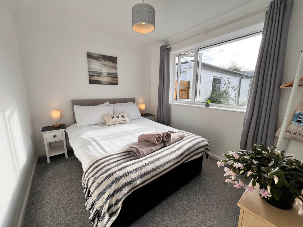 A bedroom with a bed and a window at 2 Bed Family Bungalow, WiFi, Parking, Garden, Dogs, Pentraeth
