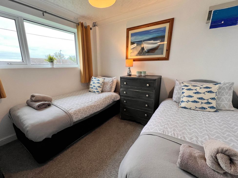 A bedroom with two single beds and a chest of drawers at 2 Bed Family Bungalow, WiFi, Parking, Garden, Dogs, Pentraeth