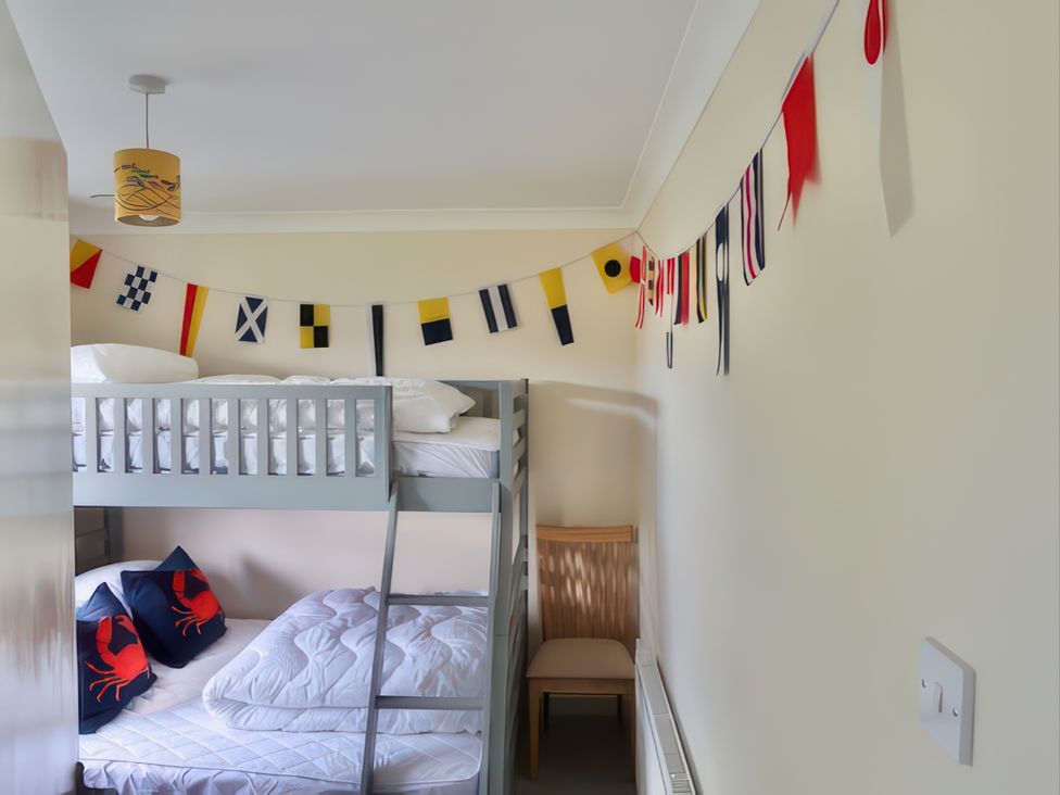 A bedroom with a bunk bed and decorative flags at Sleeps 9 KingBeds Family Friendly, Pityme near Penmayne