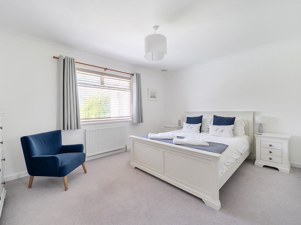 A bedroom with a bed and blue chair at Sleeps 9 KingBeds Family Friendly in Pityme near Penmayne