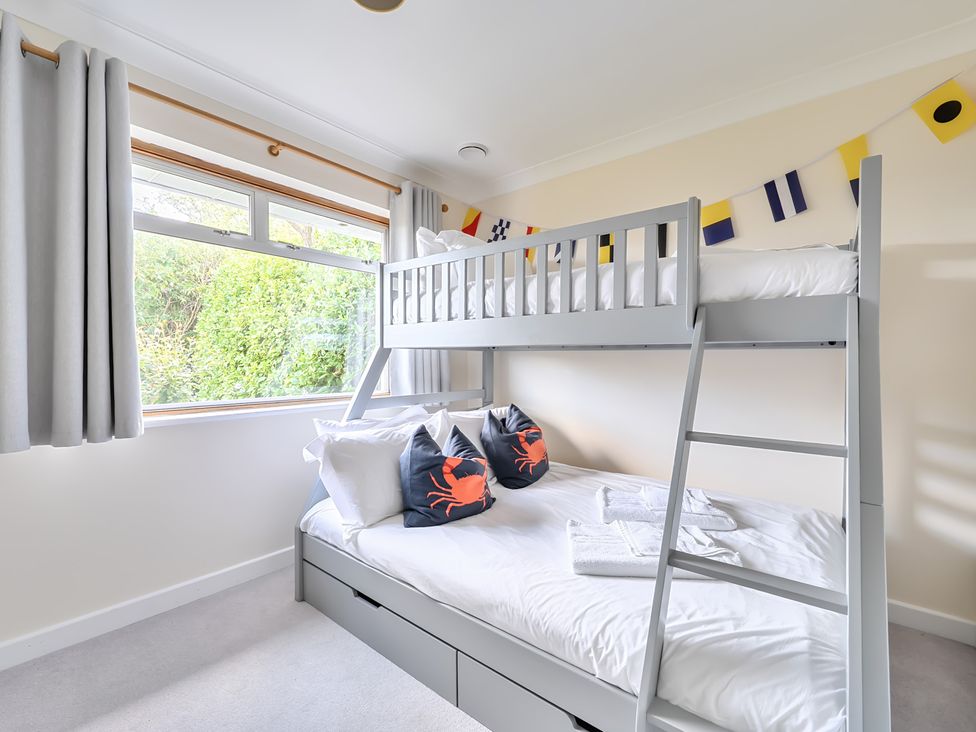 A bedroom with a bunk bed and decorative pillows at Sleeps 9 KingBeds Family Friendly in Pityme near Penmayne