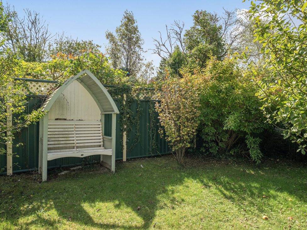 A garden with a bench and trees at Sleeps 9 KingBeds Family Friendly in Pityme near Penmayne