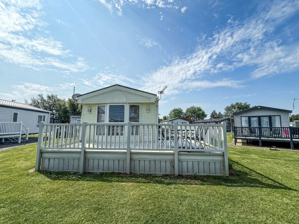 A caravan with a deck and grass area at Super 2 bed 6 berth caravan pets go free in Hunstanton
