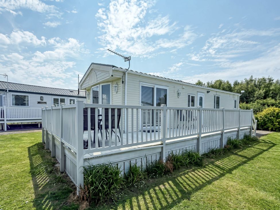 A caravan with a deck and grass area at Super 2 bed 6 berth caravan pets go free Hunstanton
