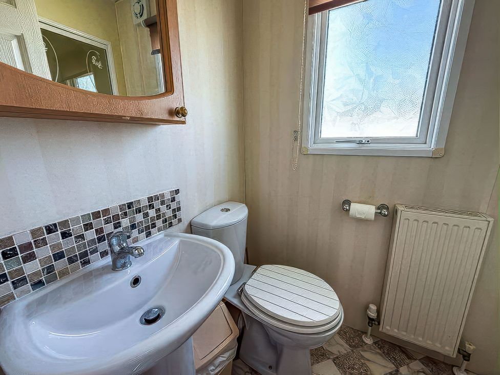A bathroom with a sink, toilet, and mirror at Super 2 bed 6 berth caravan pets go free, Hunstanton