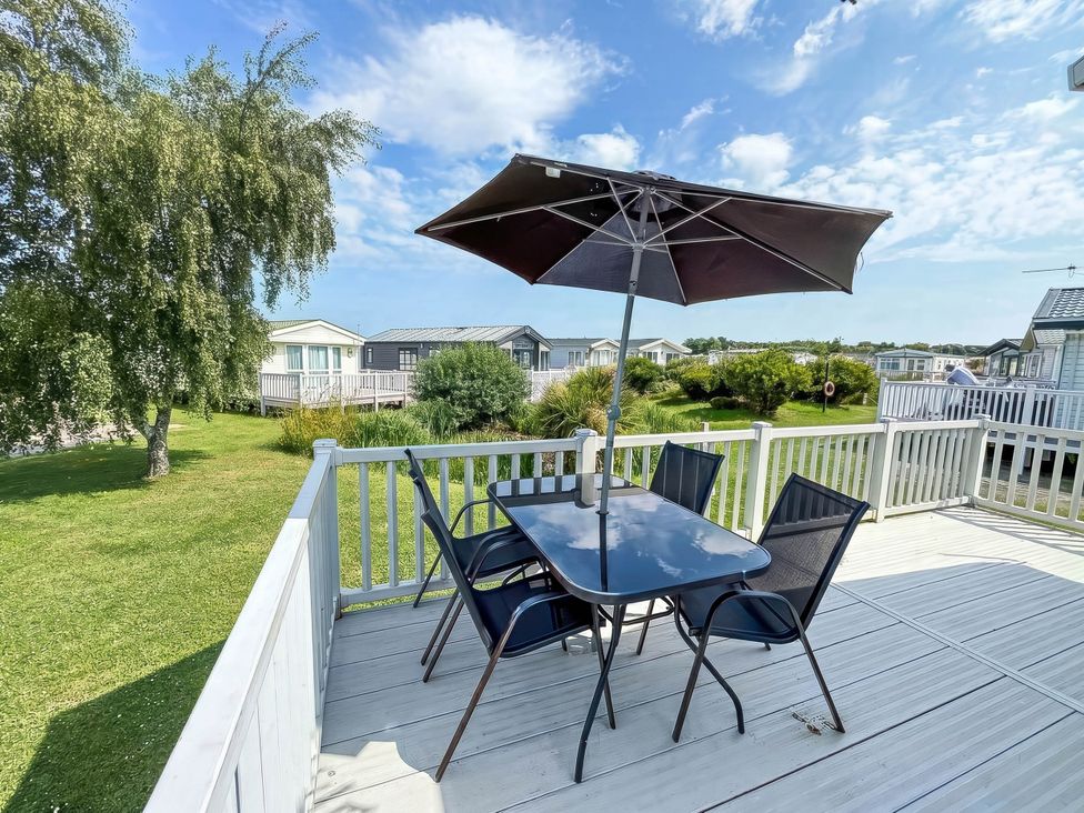 An outdoor patio with a table and chairs under an umbrella at Super 2 bed 6 berth caravan pets go free Hunstanton