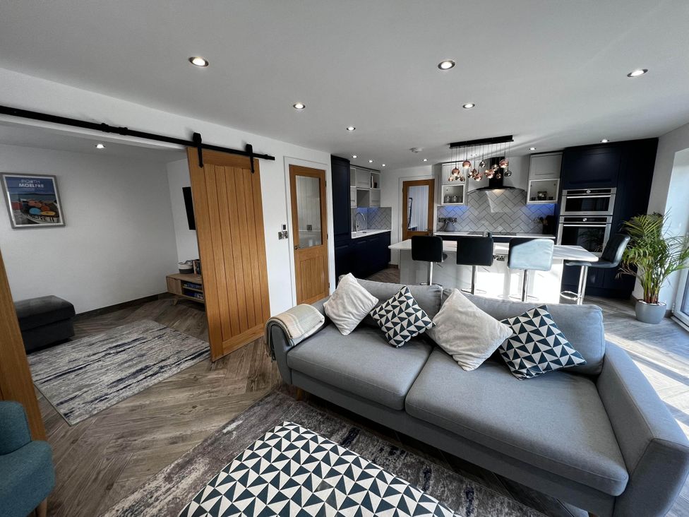 A living room with a sofa and kitchen area at a property