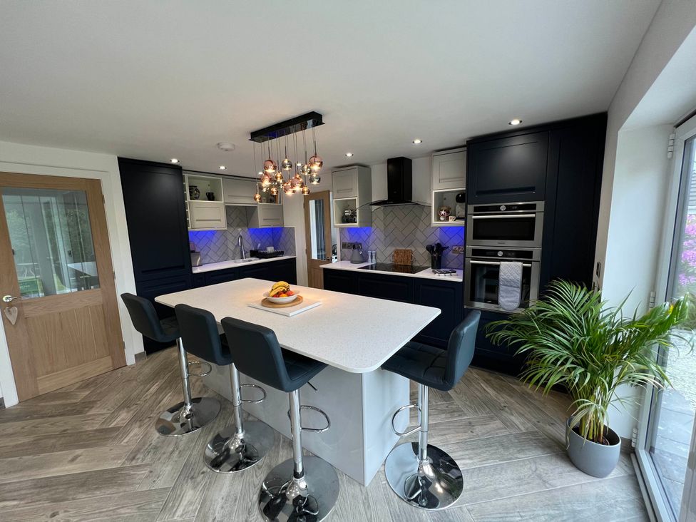 A kitchen with bar stools and appliances at The Old Barn in Manchester