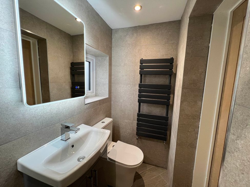A bathroom with a sink, toilet, mirror, and towel rail at The Old Barn in Manchester