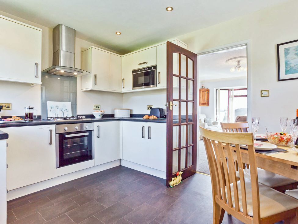 A kitchen with appliances and dining area at Lothlorien in Grange over Sands