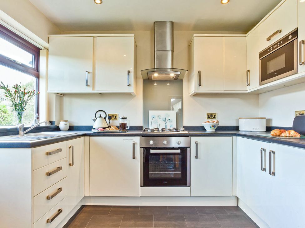 A kitchen with cabinets, oven, sink, and countertop at Lothlorien in Grange over Sands