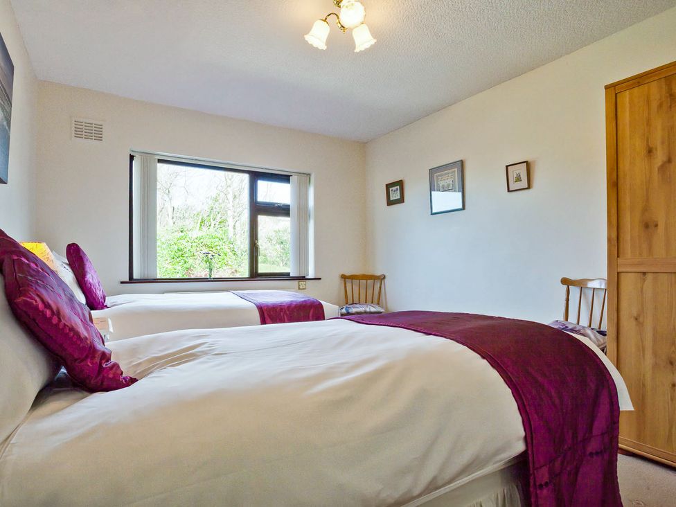 A bedroom with two beds and a window at Lothlorien in Grange over Sands