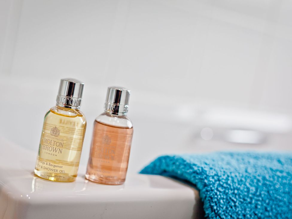 Two bottles of shower gel and a blue towel in a bathroom at Lothlorien in Grange over Sands