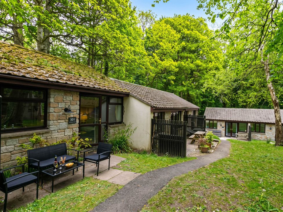 An outdoor view of a cabin with seating and trees at Painters Cottage 2Bed Chalet Free Leisure Passes Near St Ives