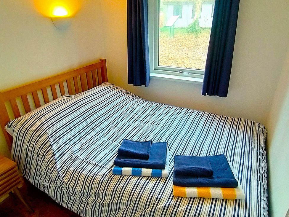A bedroom with a bed and towels at Painters Cottage 2Bed Chalet Free Leisure Passes Near St Ives