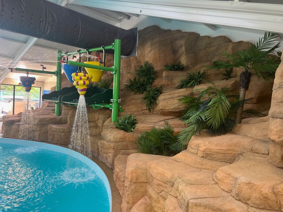 An indoor pool area with a water slide and rock formation at Painters Cottage 2Bed Chalet Free Leisure Passes Near St Ives