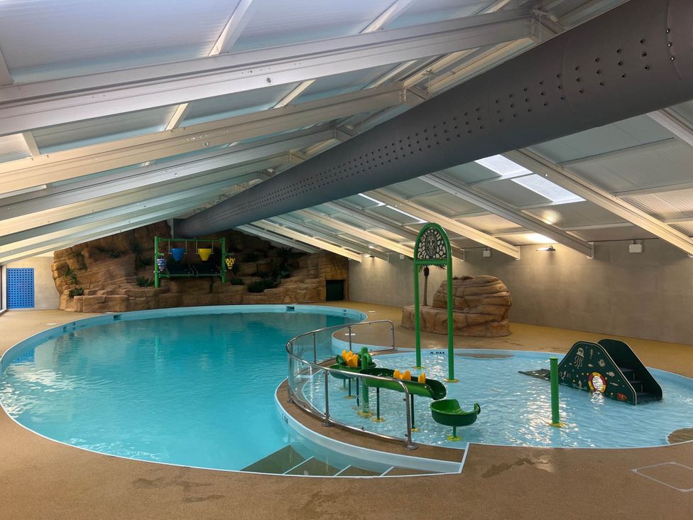 An indoor swimming pool with a slide and water features at Painters Cottage 2Bed Chalet Free Leisure Passes Near St Ives