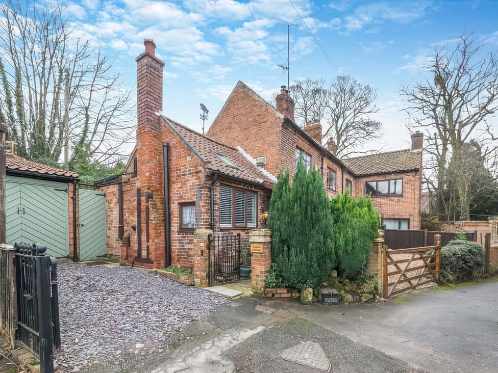 A house with a gravel driveway and surrounding trees at a property