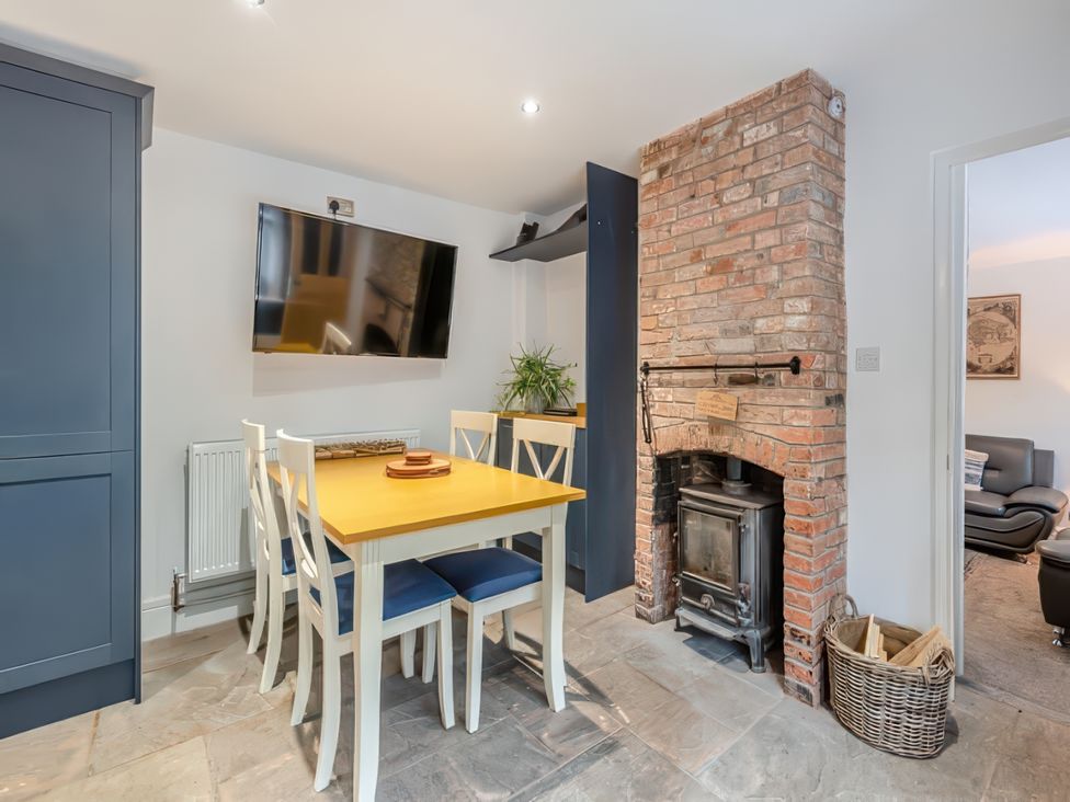 A dining room with a table and chairs next to a fireplace at The Old Barn in Manchester