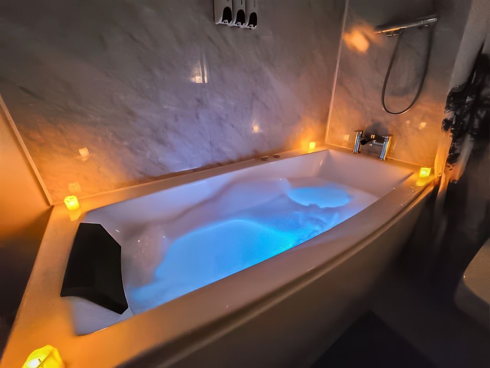 A bathtub with bubbles and candles in a bathroom