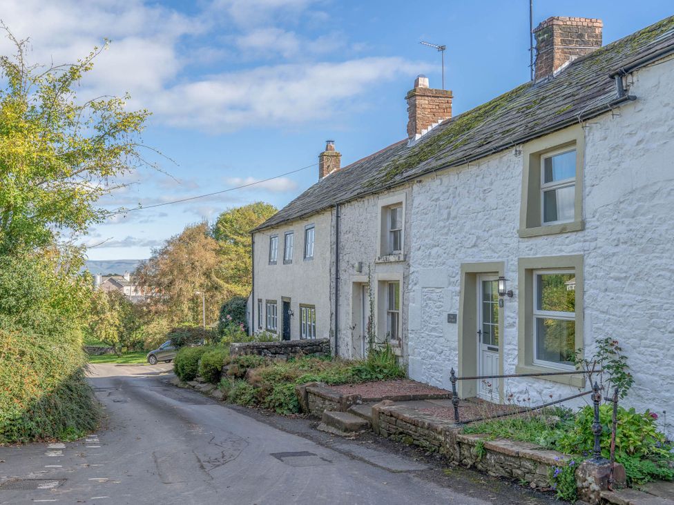 A cottage on a street with trees and shrubs at Cosy cottage near scenic walks and country pub Penrith