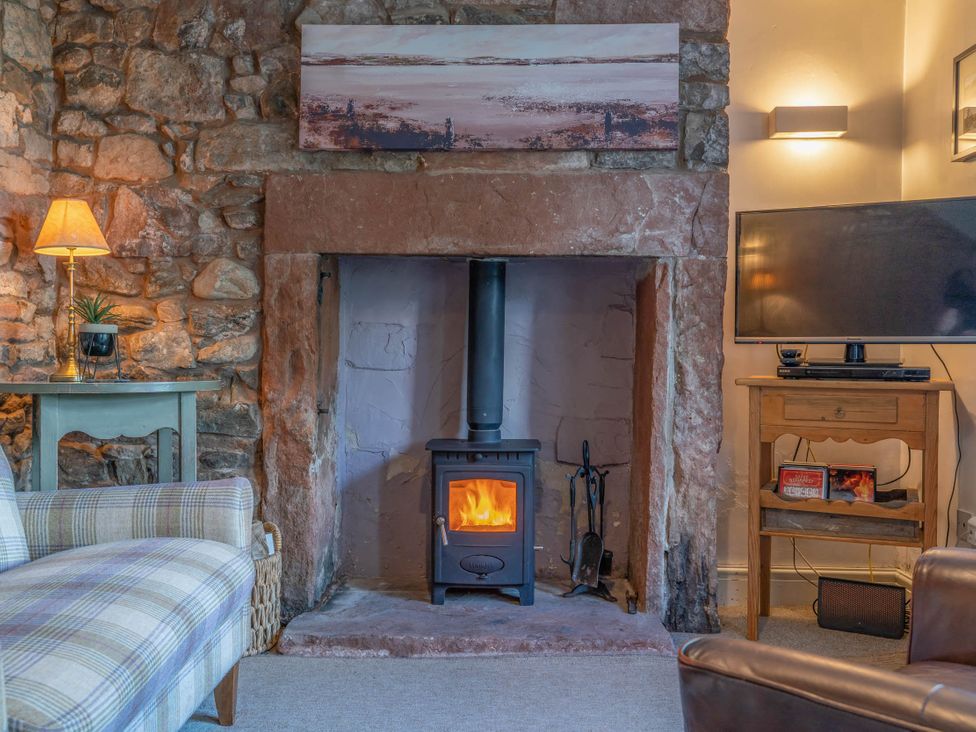 A living room with a wood stove and a television at Cosy cottage near scenic walks and country pub in Penrith